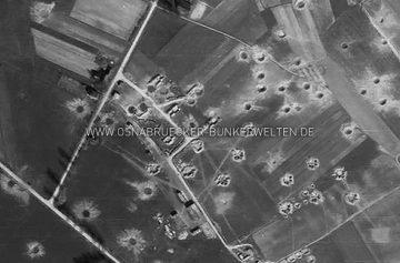 Eine US-Luftaufnahme der schweren Flak-Stellung in Voxtrup aus dem Jahr 1945. Zur Orientierung: Unten links quert die Holsten-Mündruper-Straße das Bild. Von dieser zweigt die Straße In der Steiniger Heide nach oben hin ab. Der Weg, der in der Bildmitte durch die Stellung verläuft ist die heutige Heinrich-Riepe-Straße. Luftaufnahme Flak-Stellung Voxtrup