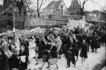 Ein großer Tross von Zwangsarbeitern und Kriegsgefangenen nach der Befreiung der Lager in Osnabrück im April 1945. Die Aufnahme entstand zwischen Ledenhof und Katharinenkirche. Im Hintergrund ist die Gehörlosenschule Alte Münze 15 zu erkennen. Auf der Rückseite wurde notiert: "Picture shows some of the hundreds of freed prisoners of all nationalities in the square. Many Russian girls can be seen among them. They are being gathered together by the military government and taken away to be fed." Befreite Zwangsarbeiter in Osnabrück, April 1945