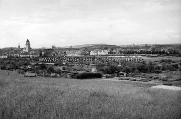 Osnabrück am 13. September 1944, angeblich kurz vor den ersten Bombenabwürfen aufgenommen. Der Fotograf hat diese Aufnahme vom Schölerberg aus gemacht (etwa auf Höhe der Sportanlage). Die Schrebergartensiedlung im Vordergrund ist heute bebaut. Im Hintergrund links sind die St. Joseph-Kirche und die alte Overbergschule zu erkennen, rechts daneben (Bildmitte) Häuser an der Overbergstraße (11-18), Wartenbergstraße und Meller Straße (114, 116). Am Standort des großen Barackenlager (rechts) befinden sich heute ein Penny-Supermarkt und diverse Neubauten. Osnabrück am 13. September 1944, kurz vor den ersten Bombenabwürfen