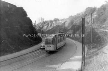 Betriebswagen 66 in der Straßenschlucht Buersche Straße, aufgenommen am 21.11.1956. Die Bunkereingänge zum Stollensystem Buersche Straße sind zu diesem Zeitpunkt schon nicht mehr als solche zu erkennen. Betriebswagen 66 Straßenschlucht Buersche Straße