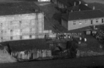 Ausschnitt aus einer Luftaufnahme der frühen Nachkriegszeit. Zu sehen ist ein Teil des Hochbunkers am Osnabrücker Hauptbahnhof mit vorgelagerten Eingangsbauwerken (rechts und unterhalb des Hauptkörpers). Rechts daneben ist im Hang eine Struktur zu erkennen, bei der es sich evtl. um einen der Stollenzugänge handeln könnte. Heute ist dieser Bereich mit einer Ziegelsteinmauer verblendet. Hochbunker Hauptbahnhof Osnabrück Nachkriegszeit