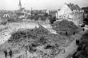 Die Trümmer des Polizeireviers III (Schinkel) an der Ecke Tannenburgstraße und Heiligenweg am Tag nach dem Luftangriff vom 6.10.1942. Zum Zeitpunkt der Aufnahme bemühten sich noch S.-H.-Männer um die Bergung der Verschütteten. Sie kamen allerdings zu spät. Im Luftschutzkeller starben 22 Menschen. Auf der Rückseite des Fotos wurde vermerkt: "1. Luftangriff auf Osnabrück am 6.10.42 / 2. Minenbombe. / 3. Das Gebäude wurde vollkommen zerstört. 5 Pol.-Beamte, 2 Pol.-Reservisten, 2 LSP.-Männer und 4 Melder sowie 9 Zivilpersonen wurden im Luftschutzraum getötet. / 4. Getroffen wurde das 3. Pol.-Revier. / 5. Aufnahme zeigt die Zerstörung." Polizeirevier Schinkel nach Luftangriff vom 6.10.1942