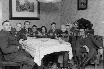 Ein weiteres Foto der Feier. Es scheint sich hierbei um ein Fest im Elternhaus des Soldaten im Hintergrund zu handeln, der von zwei Frauen (evtl. Mutter & Schwester) umgeben ist. Luftwaffe Gruppenfoto in Osnabrücker Privathaus