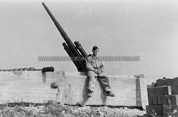 Ein Soldat vor Geschütz "D" in der Flak-Stellung auf dem Kalkhügel in Osnabrück. Zum Zeitpunkt der Aufnahme waren die Erdwälle um die Geschützstellung herum noch nicht angeschüttet worden. Geschütz Dora in einer Flak-Stellung in Osnabrück