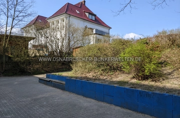 Der mutmaßliche Standort einer der Bunkerzugänge zum Stollensystem Kreuzhügel heute. Der Zugang soll sich laut ehemaligem Anwohner im heute bepflanzten Hang im Vordergrund befunden haben. Im Hintergrund ist die alte Villa Kreuzhügel 41 (heute Nr. 9) zu sehen. Angeblicher Standort Stolleneingang Kreuzhügel
