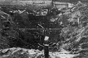 Bombenkrater am Standort des Deckungsgrabens Brunnenweg nach dem Luftangriff vom 13. Mai 1944. Am linken Bildrand sind Trümmer des Deckungsgrabens, im Hintergrund rechts der Eingang zur LS-Rettungsstelle Schinkel zu erkennen. Bombenkrater Deckungsgraben Brunnenweg