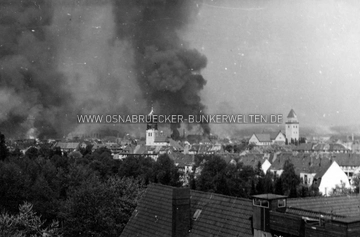Luftangriff vom 13. September 1944 auf Osnabrück. Bei dem Haus im Vordergrund müsste es sich um das Gebäude am Ravensbrink 17 handeln. Der Beobachterposten auf dem Dach existiert heute nicht mehr. Die nächstfolgenden Gebäude hinter den Bäumen wären demnach an der Friedrich-Holthaus-Straße. Im Hintergrund sind die Türme der Luther- und St. Joseph-Kirche zu erkennen. Luftangriff vom 13. September 1944 auf Osnabrück