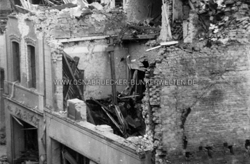 Häuser an der Ecke Krahnstraße und Hakenstraße nach dem Luftangriff vom 6.10.1942. Auf der Rückseite des Fotos wurde notiert: "1. Luftangriff auf Osnabrück am 6.10.1942. / 2. Sprengbombe. / 3. Getroffen wurden die Wohn= und Geschäftshäuser Krahnstr. 15, 16, 17/18, 19, 20, 21, 22, 34, 35, 38, 39, 41 u. 45. / 4. Die genannten Häuser wurden zerstört. / 5. Aufnahme zeight einen Teil der Zerstörungen." Auf einem angefügten Zettel wurde zudem notiert: "So sah es nach dem Luftangriff vom 10. Oktober 1942 an der Krahnstrasse/Ecke Hakenstrasse aus. Links das Schirmgeschäft Zangenberg. Dahinter das abgedeckte Dach von Nähmaschinen-Tiemann auf der anderen Strassenseite der Hakenstrasse. Aufn.: Kiefer" Krahnstraße Ecke Hakenstraße nach Luftangriff vom 6.10.1942