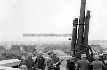 Bildunterschift: "8,8 cm beim Feuern. Einzelne engl. Flugzeuge werfen Bomben auf Osnabrück". Das Foto entstand im Jahr 1940 in der Flak-Stellung Westerberg während eines britischen Luftangriffs auf Osnabrück. Es wird sich vermutlich um den zweiten Luftangriff vom 3.7.1940 gehandelt haben. Im Hintergrund sind die noch heute existierenden Häuser Beethovenstraße 16-22 zu erkennen. Flak-Stellung Westerberg Sommer 1940