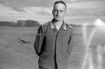 Wachtmeister einer Geschützmannschaft in der Flak-Stellung Jeggen. Der Rang eines Wachtmeisters bei der Flak ist vergleichbar mit dem Rang eines Unterfeldwebels beim Heer. Wachtmeister der Flak-Abteilung in Jeggen