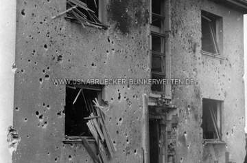 Beschädigtes Wohnhaus im Raum Osnabrück nach einem Luftangriff. Am rechten Kellerfenster ist zu erkennen, dass das Gebäude über einen eigenen Luftschutzraum verfügte, dessen straßenseitiges Fenster durch Holzbohlen vor Splittern und Druckwirkung geschützt war. Wann und wo genau die Aufnahme entstand, ist noch unklar. Im 2. Weltkrieg beschädigtes Wohnhaus im Raum Osnabrück